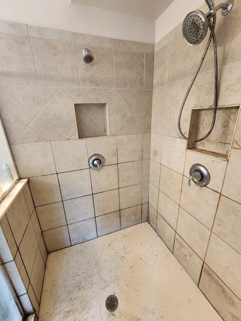 Pan-floor shower with stained grout lines before the job