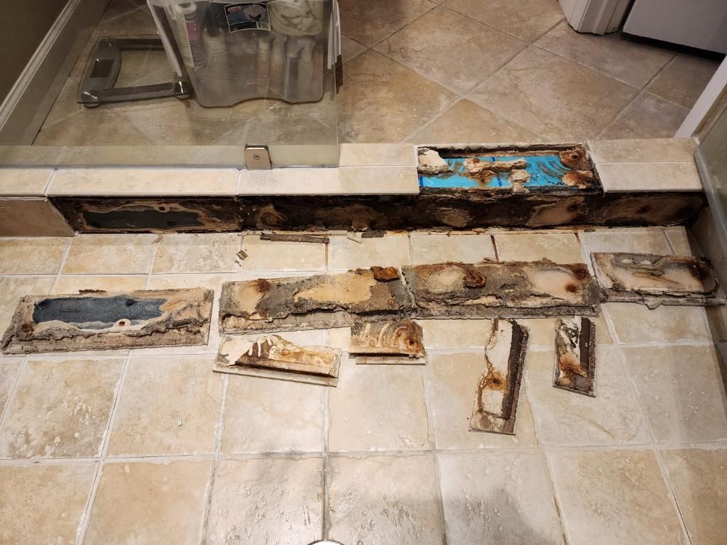 Failed shower curb with cracked tile and discolored grout