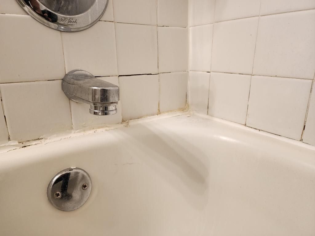 Tub surround with broken and missing grout before the repair